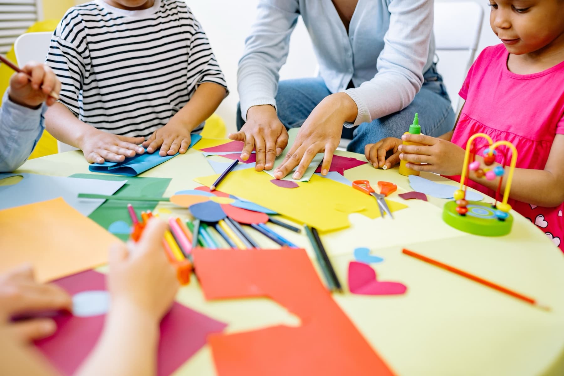 Children and a teacher making paper collages together